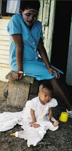 Moren smiler stolt mens barnet med bekymret mine ser vekk fra de hvite bes&oslash;kende. Foto Jenny Peers