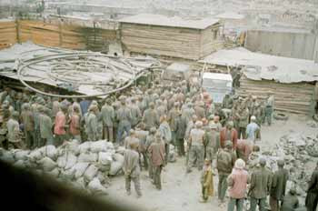 Gruvearbeiderne stimler sammen ved nedgangen til gruven. Sjakten starter under blikktaket, og det er rett f&oslash;r de f&aring;r lov til&hellip;