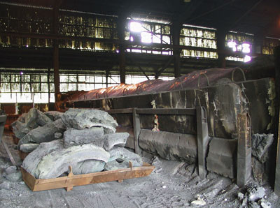 Fra ovnshus i smelteverket 2005. Til h&oslash;yre ovn i funksjon, til venstre for ovnen r&aring;materiale av silisiumkarbid som skal&hellip;